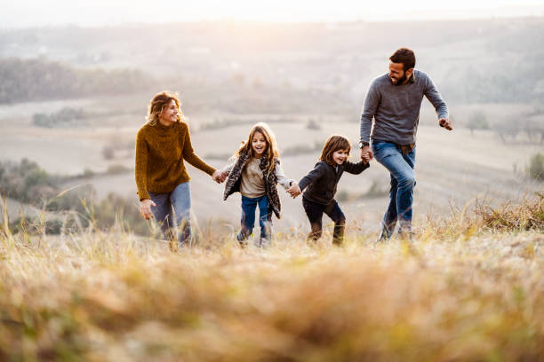 istock Playful family having fun while running in autumn day on a hill. 1145835382