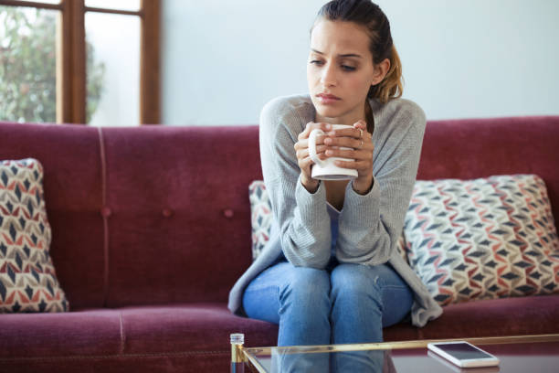 istock Depressed young woman thinking about her problems while drinking coffee on sofa at home. 1145837718