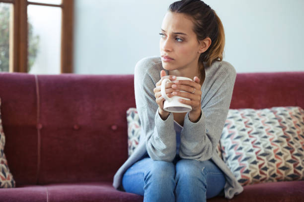 istock Depressed young woman thinking about her problems while drinking coffee on sofa at home. 1145837760