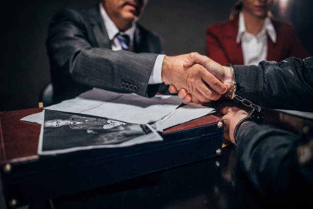 istock Arrested man shaking hand with lawyer in interrogation room 1145837957