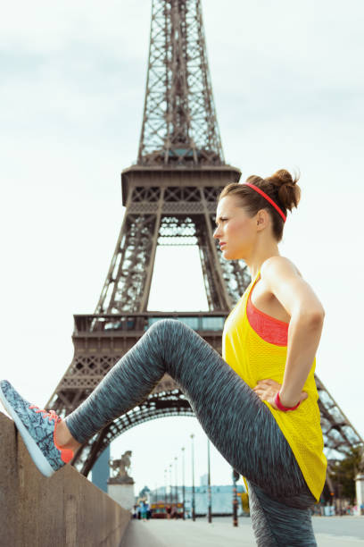 istock sports woman not far from Eiffel tower stretching 1145838054