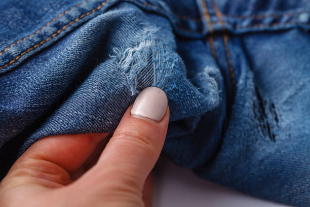 istock Hole and Threads on Denim Jeans. Ripped Destroyed Torn Blue jeans background. Close up blue jean texture 1145840572
