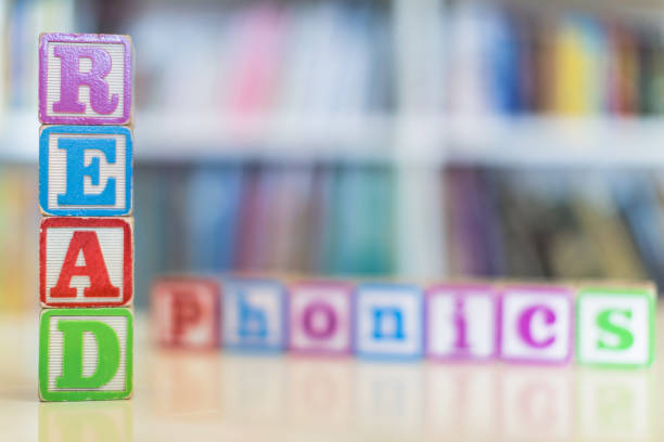 Alphabet blocks spelling the words read and phonics in front of a bookshelf stock photo