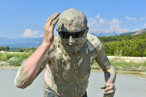 A man applies healing mud to his body. Beneficial effect on the body and skin. Healthcare. Salt and mud from the Dead Sea.