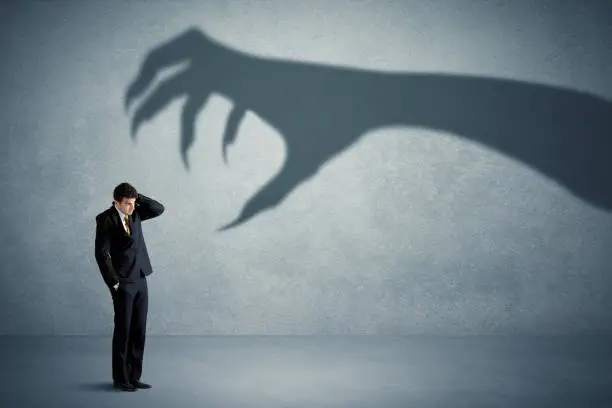 Photo of Business person afraid of a big monster claw shadow concept