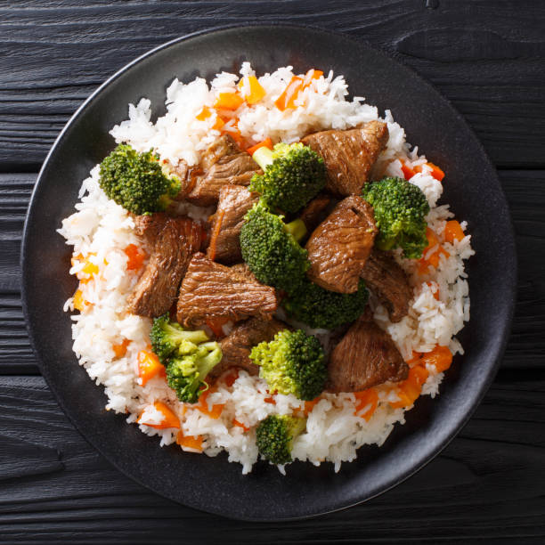 istock Roasted beef with broccoli with rice and persimmon side dish close-up on a plate. top view 1145847969