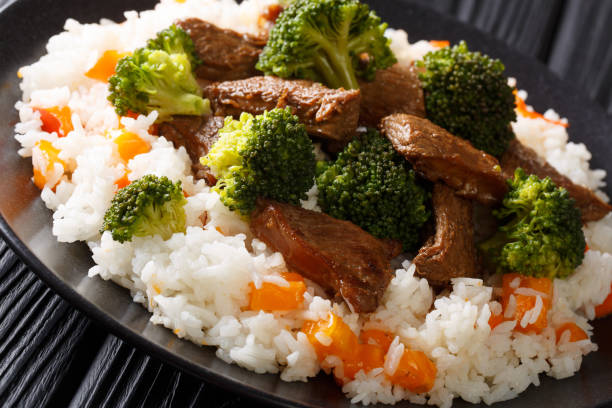 rôti de boeuf au brocoli avec riz et persimmon côté plat sur une assiette. horizontal - beef rice orange stir fried photos et images de collection