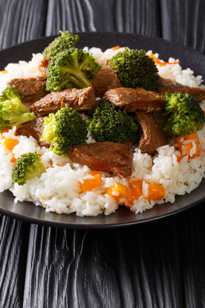 Stir-fried beef broccoli with rice and persimmon side dish close-up on a plate. vertical