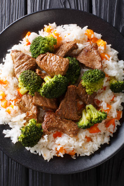 istock Asian beef with broccoli served with rice and persimmon close-up on a plate. Vertical top view 1145848125