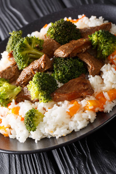 Beef with broccoli, rice and persimmon close-up on a plate. vertical