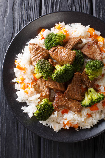 istock Stir-fried beef broccoli with rice and persimmon side dish close-up on a plate. Vertical top view 1145848234