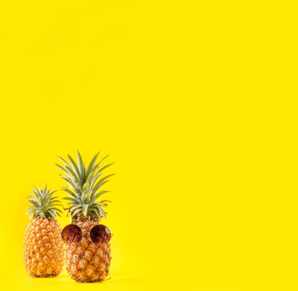 istock Creative pineapple looking up with sunglasses and shell isolated on yellow background, summer vacation beach idea design pattern, copy space close up 1145849467