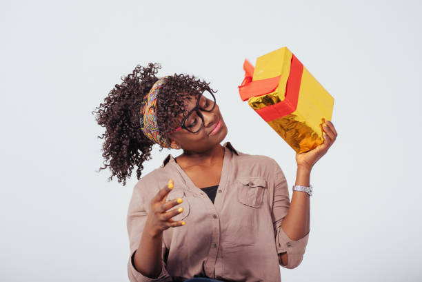 istock Looking on the gift box with joy. Holidays and celebration conception. Beautiful afro american girl with curly hair in the studio with white background 1145849470