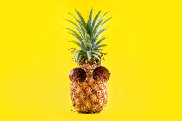 istock Creative pineapple looking up with sunglasses and shell isolated on yellow background, summer vacation beach idea design pattern, copy space close up 1145849538