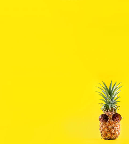 istock Creative pineapple looking up with sunglasses and shell isolated on yellow background, summer vacation beach idea design pattern, copy space close up 1145849598