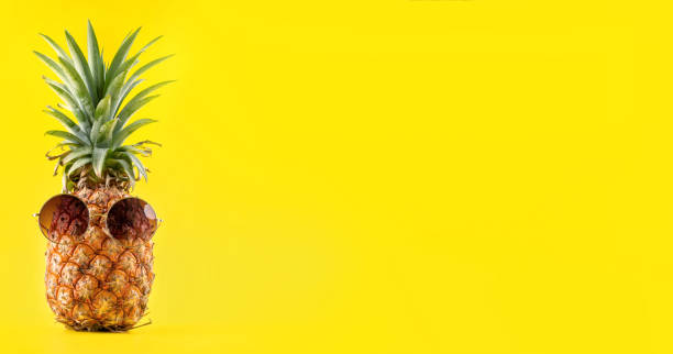 istock Creative pineapple looking up with sunglasses and shell isolated on yellow background, summer vacation beach idea design pattern, copy space close up 1145849647
