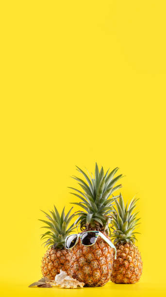 istock Creative pineapple looking up with sunglasses and shell isolated on yellow background, summer vacation beach idea design pattern, copy space close up 1145850709