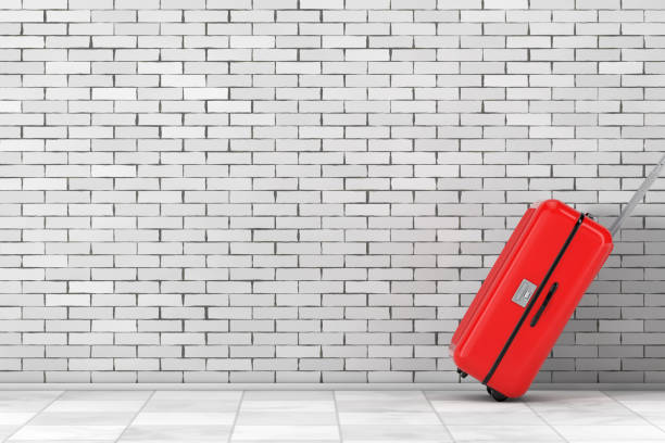 istock Vacation Concept. Red Polycarbonate Suitcase Moving from Office to Holidays Vacation in front of  Wall. 3d Rendering 1145851211