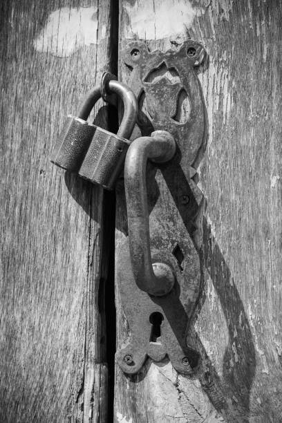 istock Monochrome Vintage Retro Styled Old Padlock on Rustic Wooden Door with Handle 1145851305
