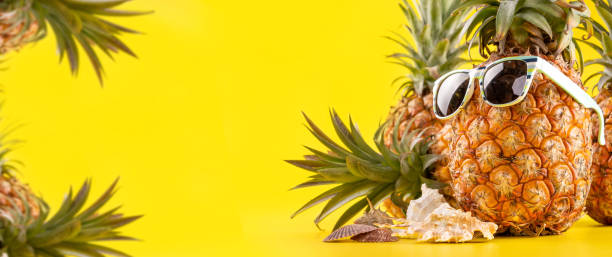 istock Creative pineapple looking up with sunglasses and shell isolated on yellow background, summer vacation beach idea design pattern, copy space close up 1145852262