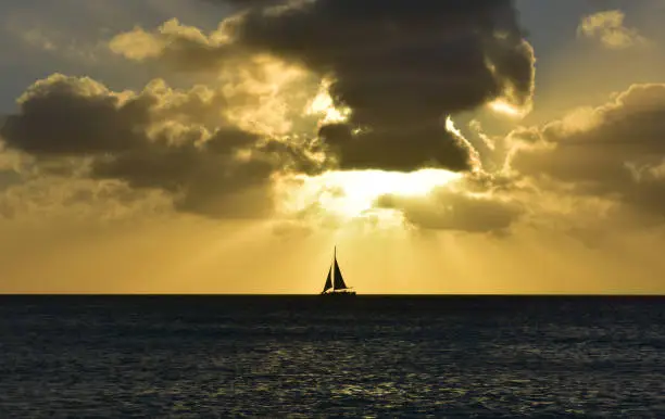 Gorgeous sailboat under a tumultous orange sky in Aruba.