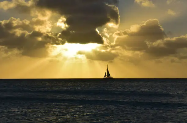 Beautiful silhouetted lone sailboat under the sunset on a beautiful day.