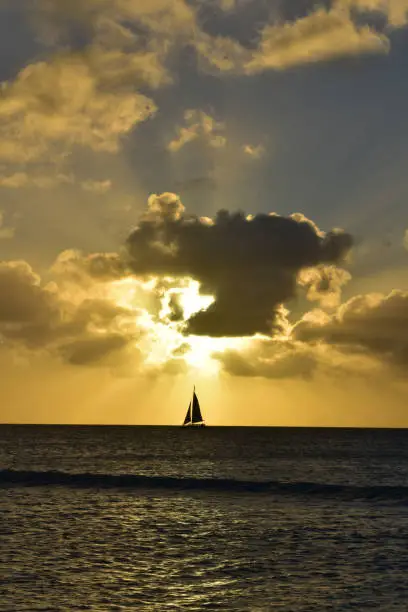 Single sailboat under a burning orange sunset in Aruba.