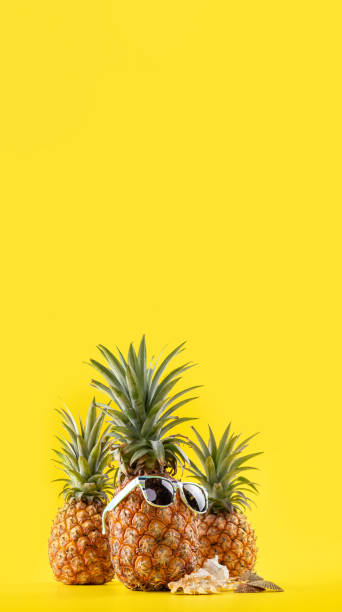 istock Creative pineapple looking up with sunglasses and shell isolated on yellow background, summer vacation beach idea design pattern, copy space close up 1145853885