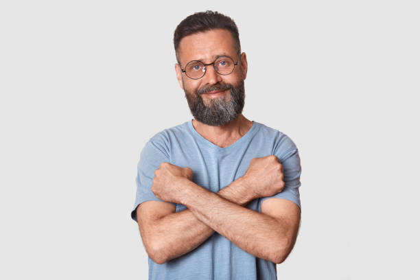 istock Kind pleasant good looking man with sincere look stands in front of camera, having confident look, holding his arms near chest, making cross, looks pleased and funny. People and emotions concept. 1145854026
