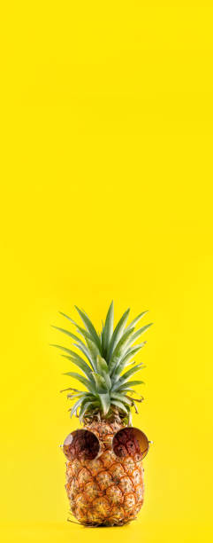 istock Creative pineapple looking up with sunglasses and shell isolated on yellow background, summer vacation beach idea design pattern, copy space close up 1145854053