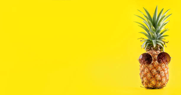 istock Creative pineapple looking up with sunglasses and shell isolated on yellow background, summer vacation beach idea design pattern, copy space close up 1145854074