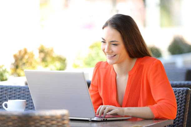 happy woman is using a laptop in a coffee shop - mobile work imagens e fotografias de stock