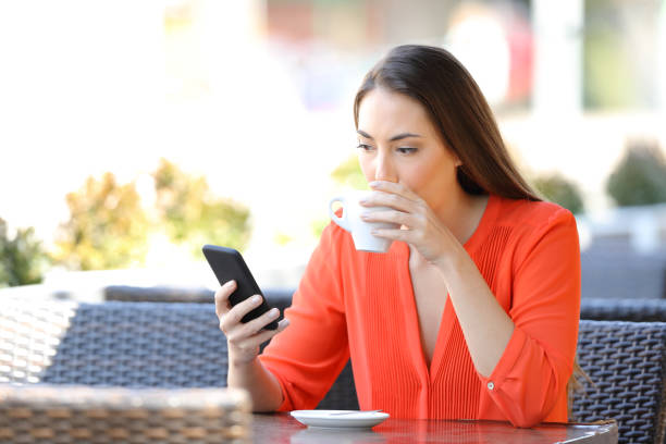istock Woman drinking coffee checking smart phone in a bar 1145855987