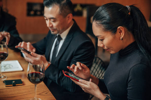 istock Man and woman using phones in restaurant 1145857768