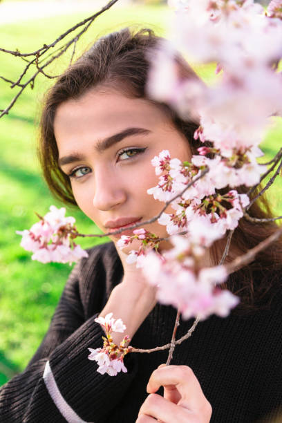 istock Girl looks out from behind blossoming tree branch 1145858647