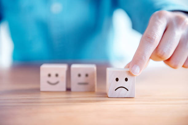 istock Hand choose sad face icon on wood cube, Service rating, satisfaction concept. 1145858979