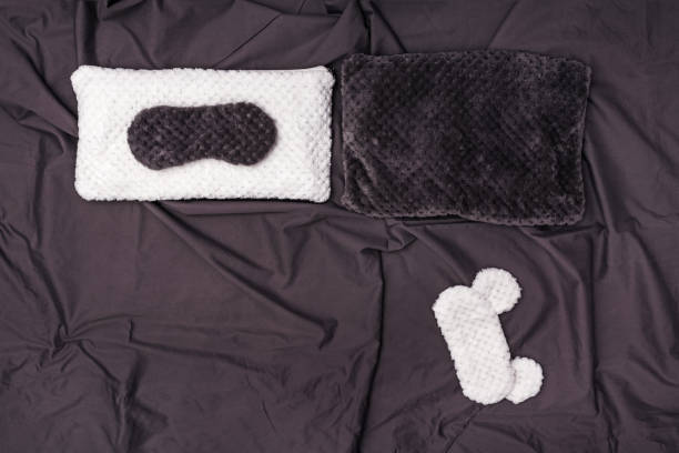 istock Two Soft pillow and two sleep mask on dark grey crumpled sheet. Two seats in bed. Top  view. Flat lay. 1145859324