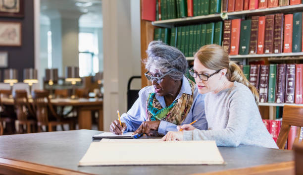 istock Two women doing research in the library together 1145861683
