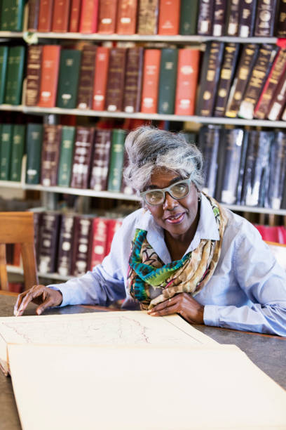 istock Woman doing research in library looking at old book 1145861913