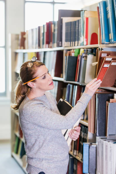 istock Mature woman looking for book in library 1145862211