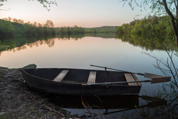 istock Boat with oars on the river shore at sunset. 1145868619