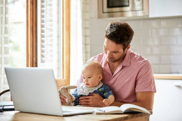 istock Father giving toy to son while sitting with laptop 1145870029