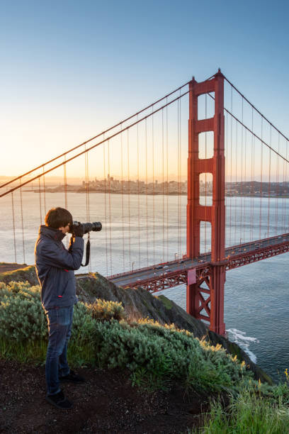 azjatycki fotograf i turysta cieszyć się robieniem zdjęć golden gate bridge podczas wschodu słońca, kultowy most i słynny punkt orientacyjny san francisco, kalifornia, usa. koncepcja fotografii podróżniczej - bridge road city golden gate bridge zdjęcia i obrazy z banku zdjęć