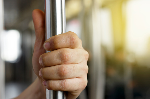 Man's hand holding a railing on a bus close up