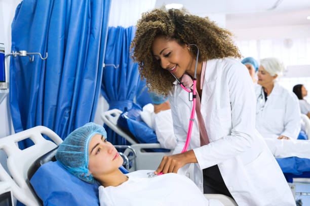 istock Afro american doctor who performs an exploration in a young patient before entering the surgery room. At the bottom of the image a nurse is observed exploring an older man. 1145873017