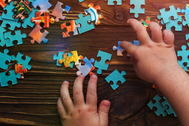 istock puzzles, human hands on a wooden table background. 1145873840