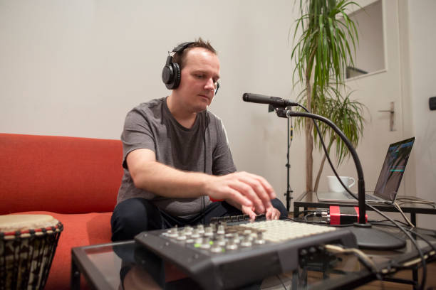 istock Professional musician recording midi keyboard in digital studio at home. He is surrounded with instruments and midi controller. Music production concept. 1145874597