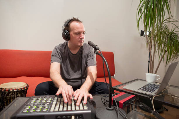 istock Professional musician recording midi keyboard in digital studio at home. He is surrounded with instruments and midi controller. Music production concept. 1145875145