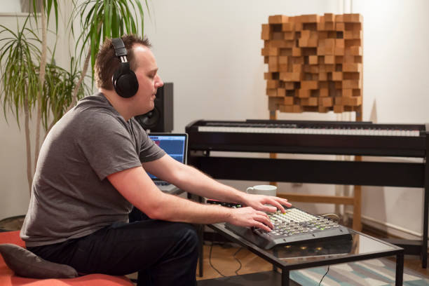 istock Professional musician recording midi keyboard in digital studio at home. He is surrounded with instruments and midi controller. Music production concept. 1145876156