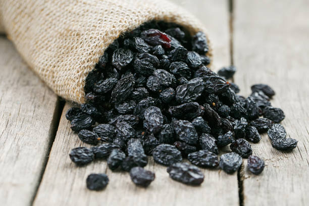 istock Black raisins in burlap bag over wooden gray table 1145879387